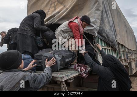 Il PG curdo della coalizione (forze democratiche siriane AKA SDF) sta portando migliaia di donne e bambini dei jihadisti di Daesh (ISIS) fuori da Baghouz, l'ultima roccaforte jihadista in Siria, in camion per farli cadere nel campo di al Hol a poche ore di distanza. Foto Stock