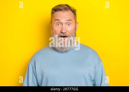 Foto di eccentrico eccitato ragazzo in pensione indossare blu maglione grandi occhi bocca aperta isolato giallo sfondo Foto Stock