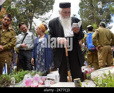 Un soldato israeliano siede accanto alle tombe dei soldati caduti nel Mt. Cimitero militare di Herzl a Gerusalemme, in occasione della Giornata della memoria di Israele per i soldati e le vittime del terrore, 8 maggio 2019. Migliaia di israeliani si sono riuniti in cimiteri militari in tutto il paese per ricordare 23.741 soldati e 3.150 vittime del terrorismo. Foto Stock