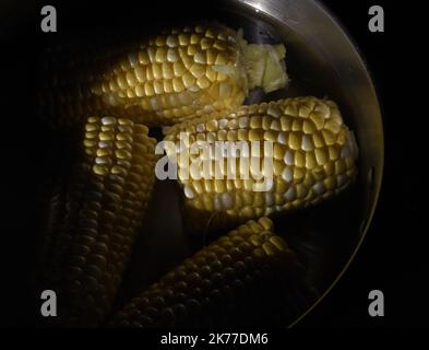 Spezzati pezzi di mais fresco sulla pannocchia in una pentola d'acqua pronta per la cottura Foto Stock