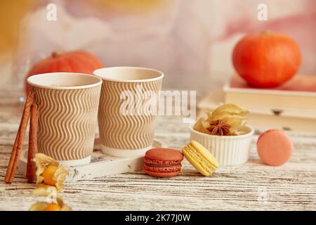 Tazze di cartone anestetico con latte di zucca e bastoncini di cannella. Tempo di caffè stagionale con amaretti tra le zucche. Accogliente atmosfera autunnale. Foto Stock