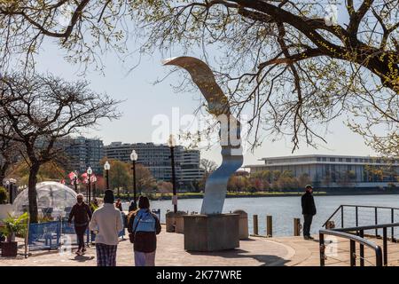 Una vista di un monumento e persone che camminano con il fiume Potomac a Washington e il Kennedy Center e Watergate Complex edifici sullo sfondo. Foto Stock