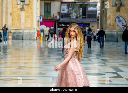 Aprile 20 2022-Napoli Italia-bella donna vestita in un abito rosa con lunghi capelli biondi posa all'interno delle gallerie Umbrerto Foto Stock