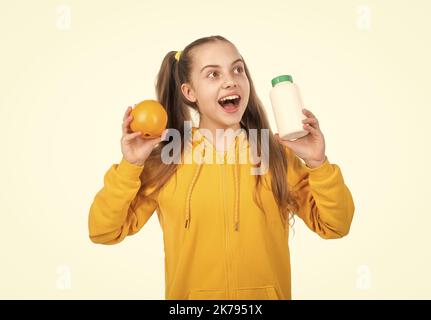 sorpreso bambino scegliere tra frutta d'arancia e vitamina pillola isolato su bianco, rimedio energetico. Foto Stock