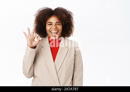 Persone aziendali. Felice afroamericano businesswoman lode smth eccellente, dà complimento, feedback positivo, si trova su sfondo bianco Foto Stock