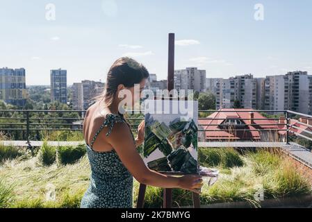 Giovane artista dipinge sullo sfondo della città Foto Stock