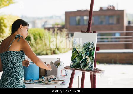 Giovane artista donna dipinge con una spatola sulla tela Foto Stock