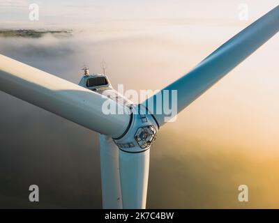 Primo piano sulle eliche di una turbina eolica durante una mattinata nebbiosa e l'alba. Energia verde. Turbina eolica alla nebbia mattutina Foto Stock