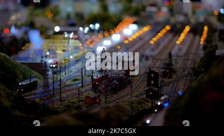 Notte binari ferroviari vuoti vicino alla stazione ferroviaria con luci nella notte buia. Una stazione ferroviaria vicino alla ferrovia. Foto dalla ferrovia. Immagine sfocata. Lig sfocato Foto Stock