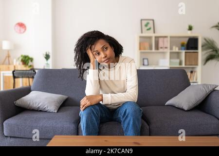 Depresso giovane adulta ispanica donna latina seduta sul divano a casa Foto Stock