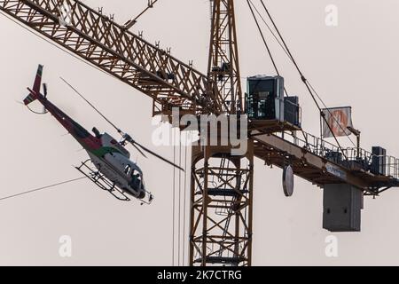 ©Arnaud BEINAT/Maxppp. 2021/02/24, Metz, Mosella, Francia. Un hélicoptère de la société Blugeon transporte des poutrelles métalliques a l'élingue pour la construction d'une tribune du stade de football Saint-Symphorien de Metz Foto Stock