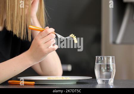 ©PHOTOPQR/l'ALSACE/Vanessa MEYER ; ; 02/06/2021 ; une jeune fille anorexique devant une assiette presque vide et un verre d'eau tient une fourchette avec une pâte. Les Troubles du comportement alimentaire ont augmenté pendant la crise sanitaire. - anoressia Foto Stock