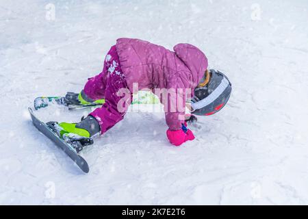 Inverno, bambini snowboarder sulla pista da sci in giacca rosa brillante. Foto Stock