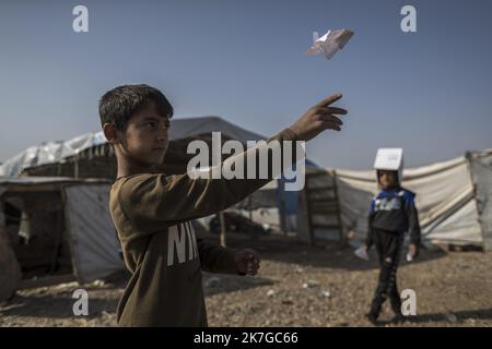 ©Christophe Petit Tesson/MAXPPP - 26/11/2021 ; HASSAN SHAM ; IRAQ - un enfant lance un avion en papier au 'camp U3' a Hassan Sham, a 30 km a l'est de Mossoul, le camp est sorveglianza commune des autorites kurde et Irakienne. Un espace de ce camp de reifies est Reserve aux anciens mineurs combattant de l'Etat Islamique, non condamne par la justice ils n'ont pas le droit de sortir du camp . U3 campo a Hassan Sham. Questo campo profughi a 30 km a est di Mosul è gestito dalle autorità curde. Una zona nel campo è riservata ai giovani combattenti dell'ex Stato islamico, non condannati da jcourt che fanno Foto Stock