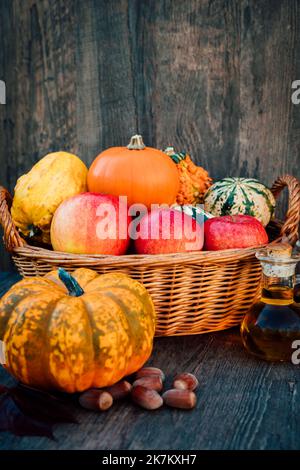 Autunno ancora vita composizione di mele zucche in un cesto di vimini sul tavolo Foto Stock