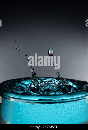 Gocce d'acqua in una tazza di vetro di colore blu. Foto Stock