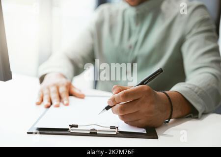 Primo piano di un uomo d'affari che lavora con i documenti mentre è seduto in ufficio Foto Stock