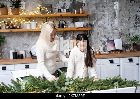 Ragazza giovane che aiuta sua madre che decora l'albero di Natale, Foto Stock