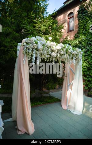 Cerimonia nuziale. Molto bello ed elegante arco di nozze, decorato con vari fiori freschi, in piedi nel giardino. Giorno di nozze. Fiori freschi de Foto Stock