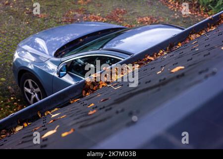 Un ritratto di una grondaia del tetto intasata con foglie autunnali durante la stagione autunnale. Le foglie di betulla colorate sono nel modo per l'acqua piovana e lo faranno andare Foto Stock