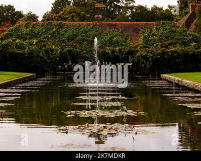 Vista sul laghetto d'acqua rettangolare formale che conduce ad una fontana nei giardini di RHS Wisley. Foto Stock