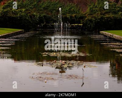 Vista sul laghetto d'acqua rettangolare formale che conduce ad una fontana nei giardini di RHS Wisley. Foto Stock