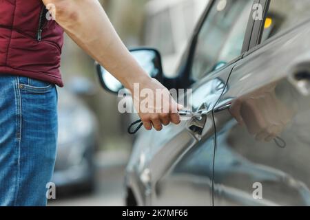 Un uomo apre la porta di un'auto con una chiave. Batteria scarica nel telecomando Foto Stock