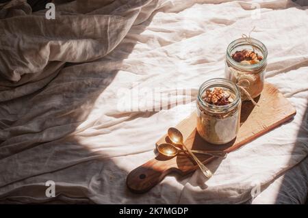 Delizioso durante la notte non cuoco vegan crudo farina d'avena rustica in un vaso con banana e datteri su sfondo minimalistic bello e neutro beige Foto Stock