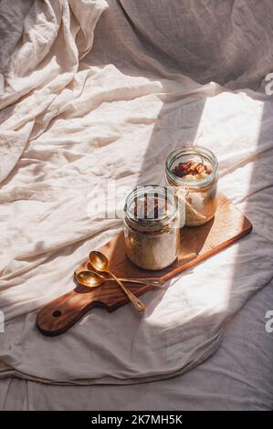 Delizioso durante la notte non cuoco vegan crudo farina d'avena rustica in un vaso con banana e datteri su sfondo minimalistic bello e neutro beige Foto Stock