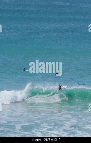 Un surfista che cavalca un'onda a Fistral Bay a Newquay in Cornovaglia in Inghilterra nel Regno Unito. Foto Stock