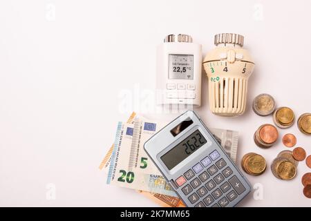 Berventionelles Heizungsventil gegen elektronische Regelung mit Taschenrechner und Geldscheinen Foto Stock