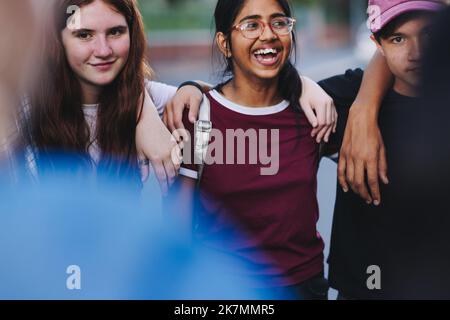 Gruppo di attivisti adolescenti felici che si abbracciano e si trovano in un cerchio. Giovani multiculturali che si battgono per l'uguaglianza e la diversità. Foto Stock