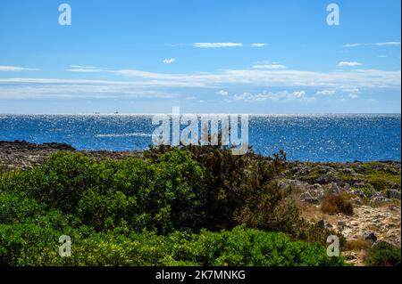 L'aspro e roccioso paesaggio del Parco Naturale Regionale di Porto Selvaggio con il Faro di Isola Sant'Andrea all'orizzonte, Puglia, Italia. Foto Stock