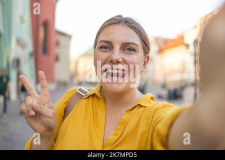 Ragazza giovane prendere selfie dalle mani con il telefono sulla strada estiva città. Concetto di vita urbana. Cracovia, Polonia Foto Stock