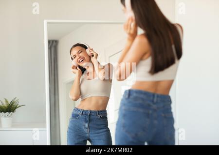 Donna che indossa le cuffie canzone di canto ascoltare la musica a casa Foto Stock