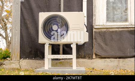 Una pompa di calore aria-aria è installata sulla facciata esterna della vecchia casa. Foto Stock