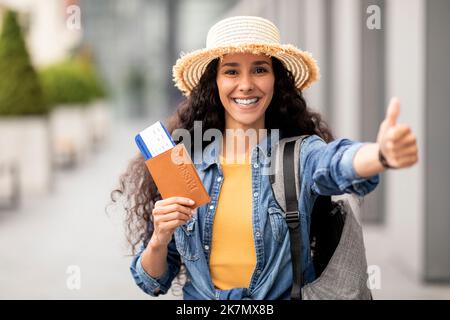 Donna mediorientale positiva che mostra il passaporto e il pollice in su Foto Stock
