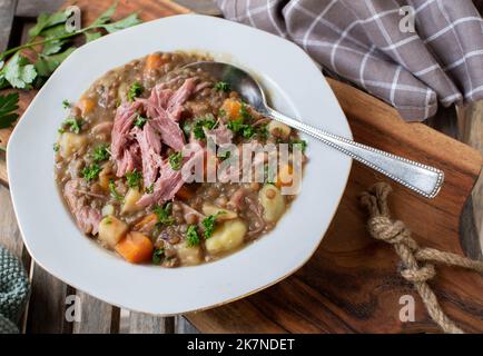 Piatto con stufato di lenticchie appena cotto con carne di maiale, verdure e patate Foto Stock