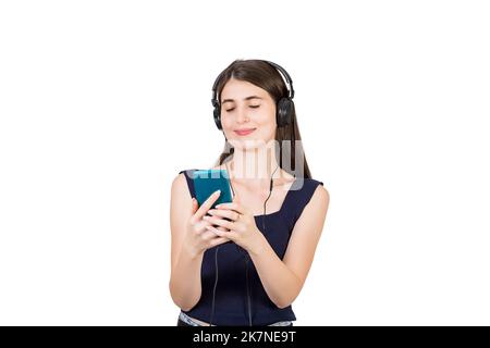 Donna informale e rilassata che ascolta musica calmante con le cuffie, tenendo il telefono con gli occhi chiusi isolato su sfondo bianco Foto Stock