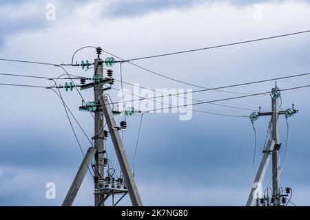 Poli di alimentazione della linea ad alta tensione su sfondo cielo nuvoloso. Trasmissione di elettricità. Foto Stock