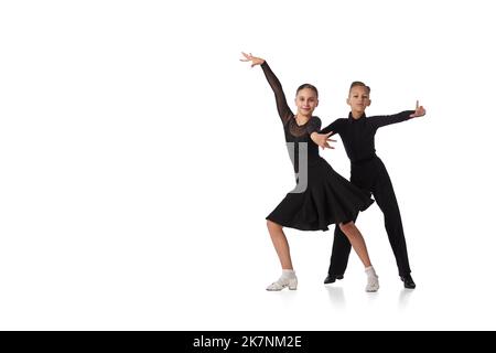 Coppia di danza. Due bambini, bambina e ragazzo in età scolastica in costume nero da ballo ballo ballo ballo danza isolata su sfondo bianco. Movimento, azione, hobby Foto Stock