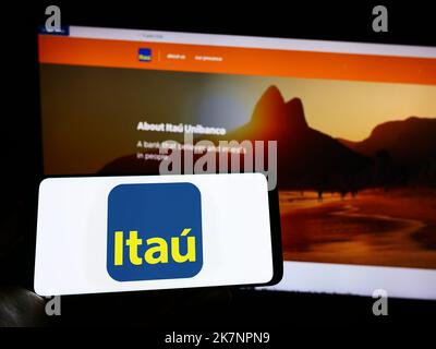 Persona che tiene il cellulare con il logo della società brasiliana Itau Unibanco Holding SA sullo schermo di fronte al sito web aziendale. Messa a fuoco sul display del telefono. Foto Stock