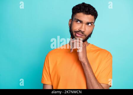 Primo piano foto di uomo pensivo indossare abiti arancioni alla moda interessato guardare spazio vuoto dilemma domanda isolato su sfondo di colore ciano Foto Stock