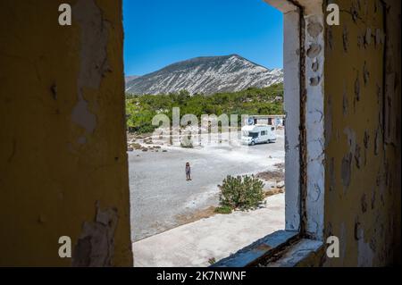 Famiglia con camper esplorando edifici di fabbrica abbandonati a Creta, Grecia. Visita alle rovine del complesso industriale abbandonato, lato ovest dell'isola di Cret Foto Stock