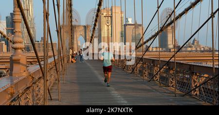 Un uomo in pantaloncini corti e una canotta fa jogging sul Ponte di Brooklyn Foto Stock