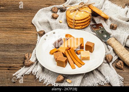 Brunost norvegese con biscotti e noci. Cibo sano e mangiare, ingrediente biologico per la prima colazione. Tradizionale formaggio marrone scandinavo, retro in legno Foto Stock