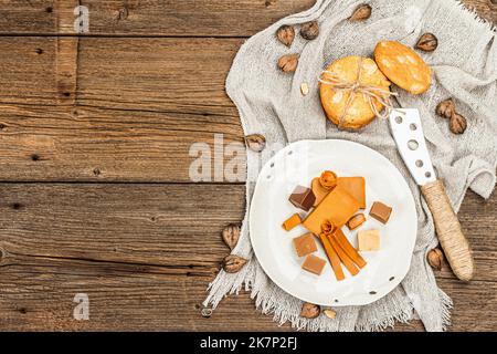 Brunost norvegese con biscotti e noci. Cibo sano e mangiare, ingrediente biologico per la prima colazione. Tradizionale formaggio marrone scandinavo, retro in legno Foto Stock