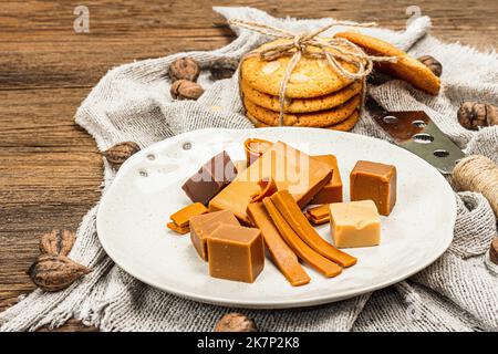 Brunost norvegese con biscotti e noci. Cibo sano e mangiare, ingrediente biologico per la prima colazione. Tradizionale formaggio marrone scandinavo, retro in legno Foto Stock