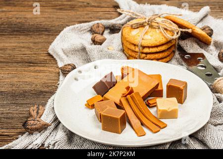 Brunost norvegese con biscotti e noci. Cibo sano e mangiare, ingrediente biologico per la prima colazione. Tradizionale formaggio marrone scandinavo, retro in legno Foto Stock