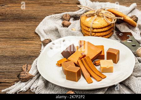 Brunost norvegese con biscotti e noci. Cibo sano e mangiare, ingrediente biologico per la prima colazione. Tradizionale formaggio marrone scandinavo, retro in legno Foto Stock